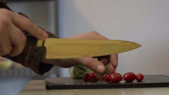一名男子将樱桃西红柿切成自制鳄梨色拉酱。