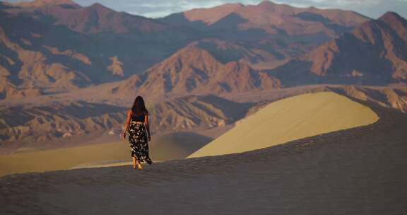 裙子摇摆女人走过沙丘到边缘观山