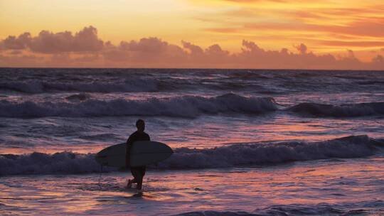 冲浪者在日落时走出水面