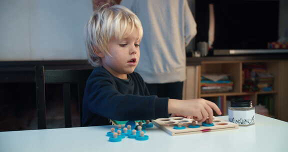 快乐的男孩坐在客厅的桌子旁玩教育游戏