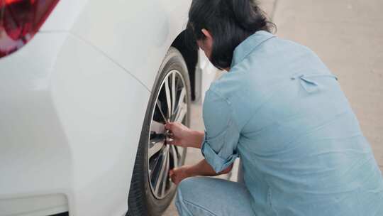女人检查汽车轮胎压力假期旅行路上的车辆问