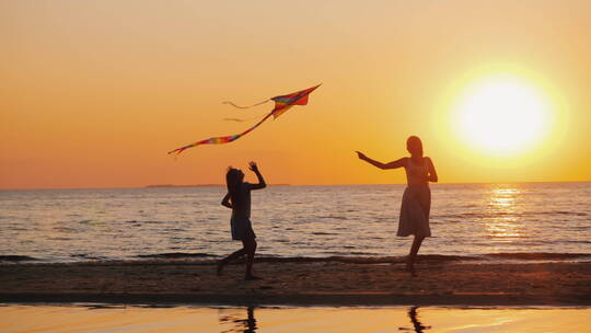 黄昏下在海滩上放风筝的母女视频素材模板下载