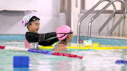 两个在泳池中玩耍玩水的中国女孩