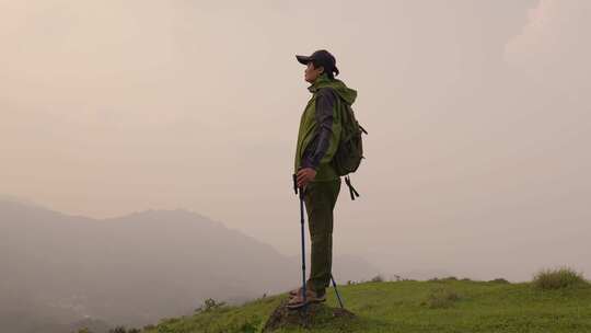 登山者手持登山杖站在山顶眺望远方