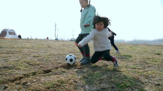 冬季在公园草坪上踢球的两个女孩