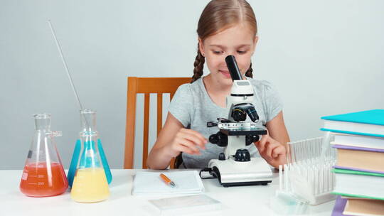 女孩使用显微镜并记录下来视频素材模板下载
