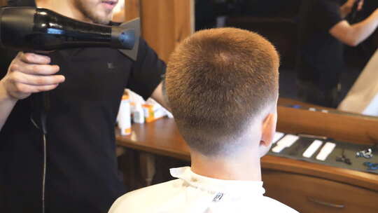 理发师在用刷子和吹风机清洁他的顾客剪下的头发