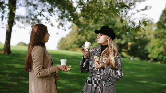 两个女人在公园边吃东西边聊天