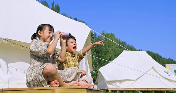 孩子坐在帐篷下看万花筒玩耍