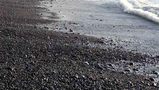 黑色卵石海滩和海浪的特写视频素材模板下载