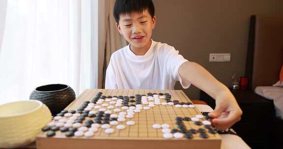 可爱的男孩在窗边下围棋