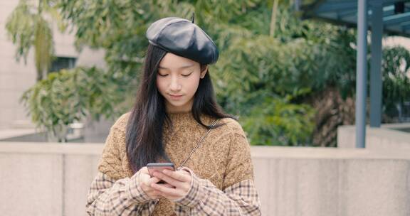 女大学生在学校边走路边看手机