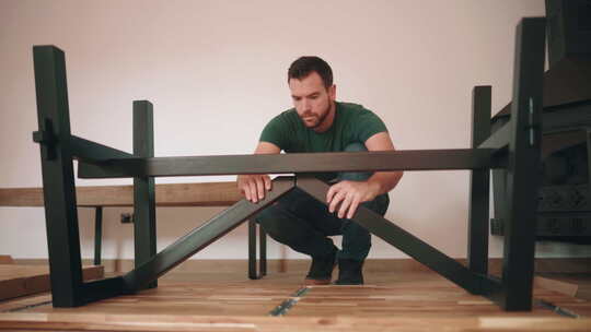 男人连接木桌的金属腿-宽镜头