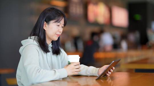 年轻女子在咖啡店使用平板电脑上网