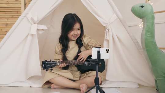 女孩在手机前弹尤克里里
