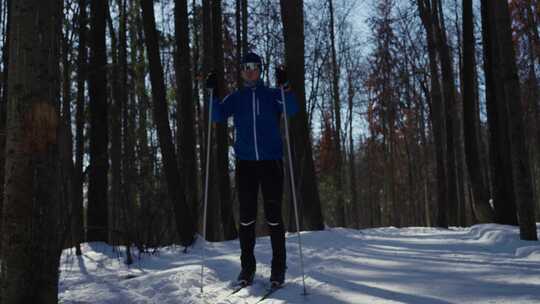 阳光明媚的一天，一名男子滑雪者正在从森林