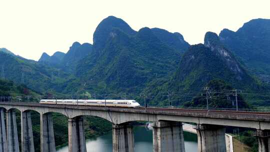 航拍山谷隧道中驶出的高铁列车