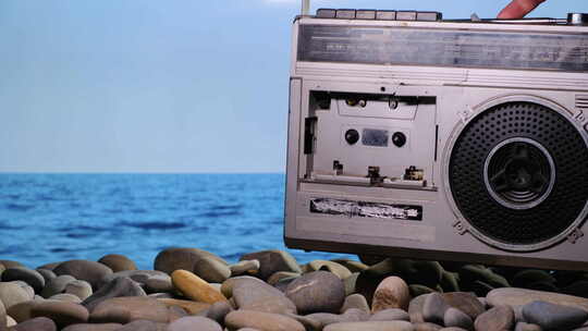 Vacationer放在石头海滩老式复古收音机录音机和放在录音带上