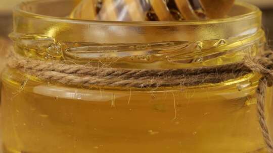 蜂蜜从勺子纺锤流入一罐柠檬水背景上的蜂蜜罐