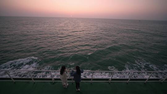 年轻女孩在轮船甲板上看海上夕阳