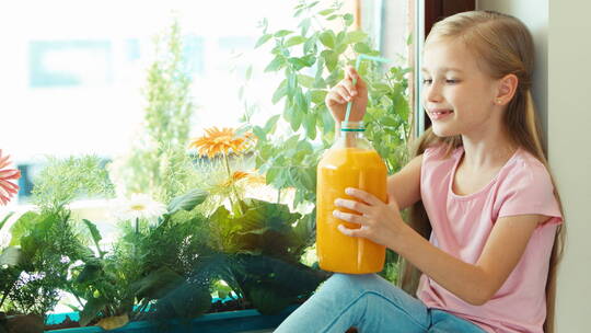 女孩喝着大瓶橙汁并对着镜头微笑