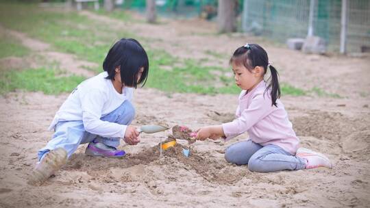 两个小女孩户外玩沙子