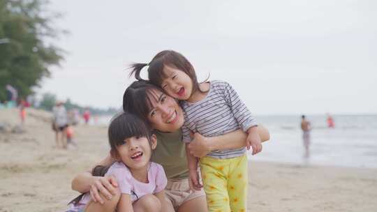 亚洲幸福家庭妈妈和孩子的肖像晚上在海滩上玩沙子，背景是大海。