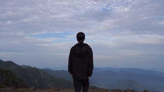 女性青年站在山顶看风景背影看远山感受自然