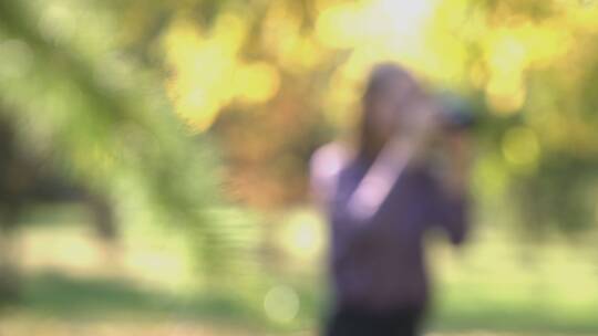 拿相机在草地上拍摄风景的女人