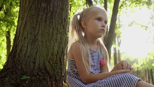 公园里大树下坐着的小女孩视频素材模板下载