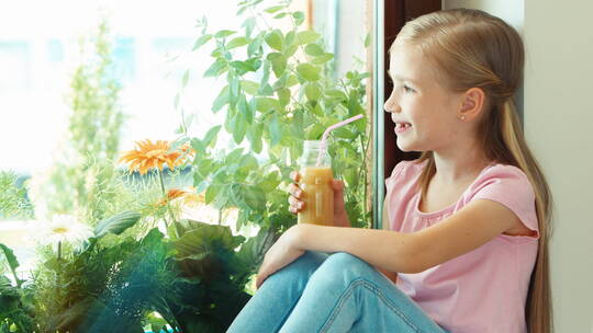女孩坐在窗台上用吸管喝果汁
