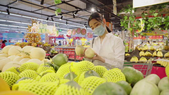 戴口罩的青年女人在超市选购水果