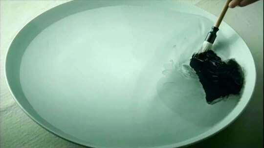 毛笔蘸墨于瓷盘的素材