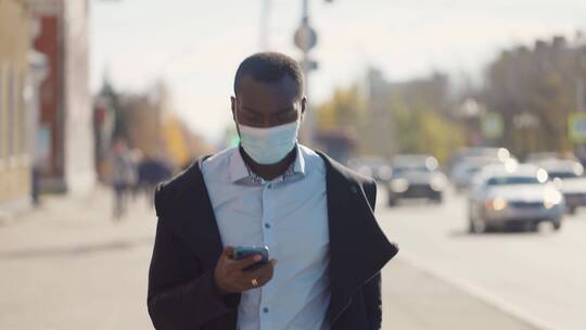 男人戴口罩在街上玩手机