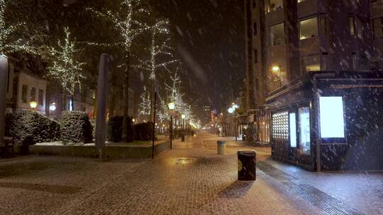 夜晚下雪天行人匆匆走在霓虹灯闪烁的街道