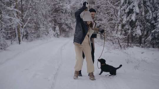 一对夫妇带着他们的狗在雪地里跑步