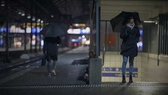 火车站的雨夜拿着雨伞等待交通的通勤者