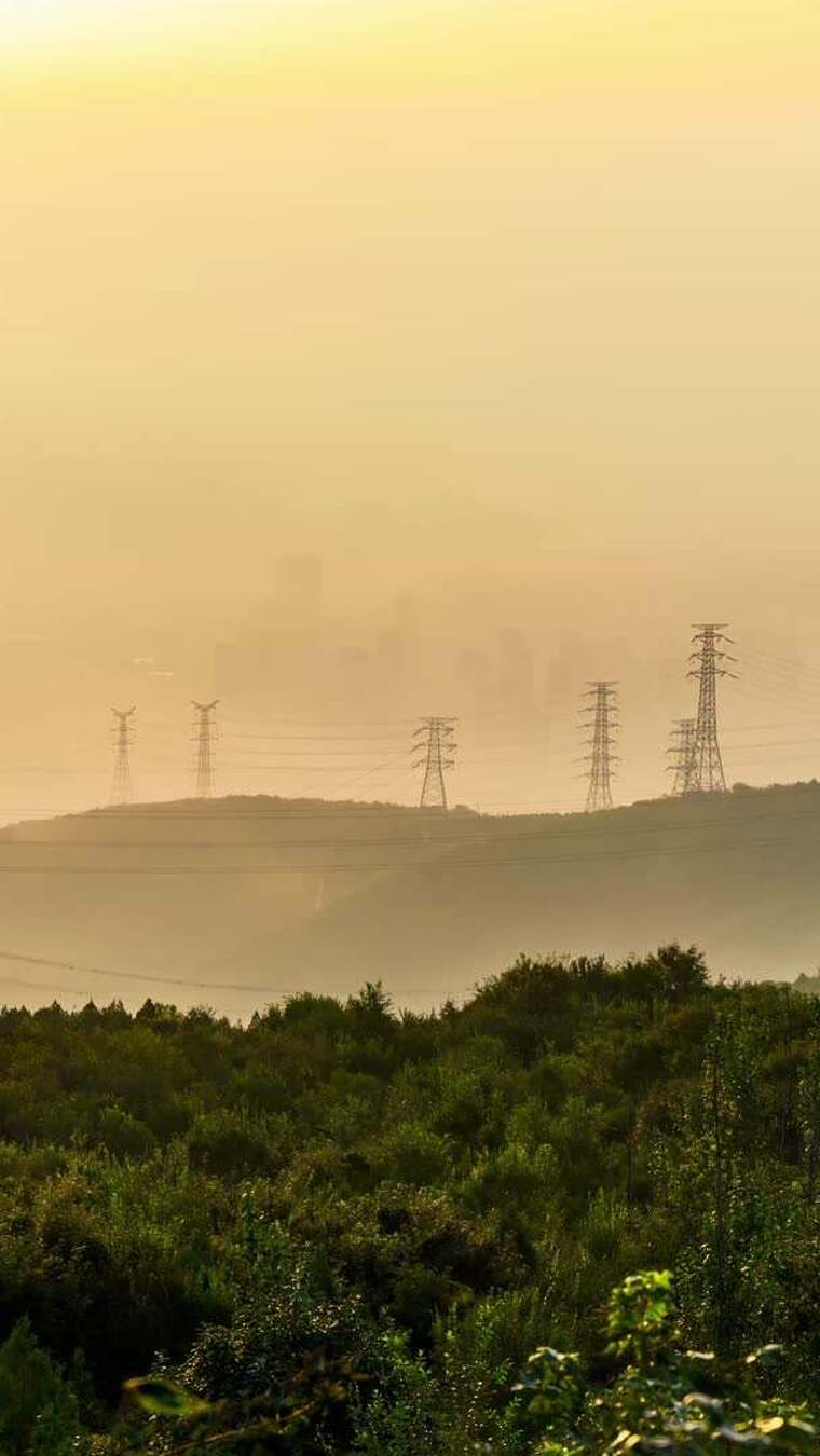 山林间晨曦中的输电塔景观