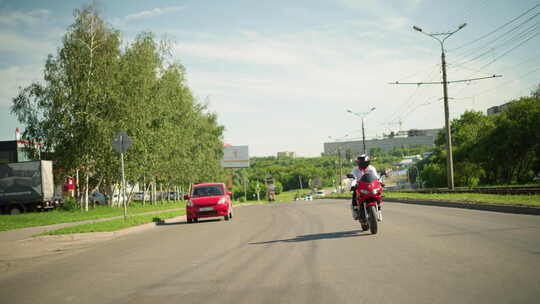 摩托车手在市区高速公路上快速骑行，红色汽