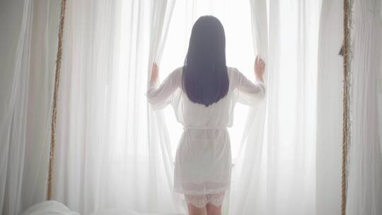女生起床拉开窗帘看向窗外风景