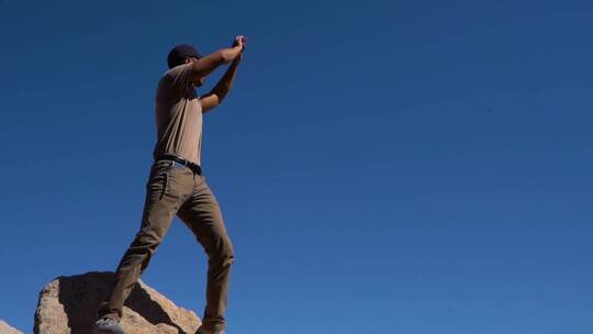 男人站在岩石上摆手
