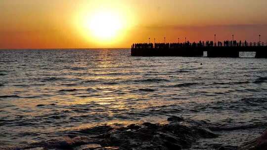 海面日落晚霞金海湾栈桥人群剪影
