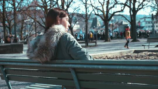 女人坐在公园长椅上视频素材模板下载