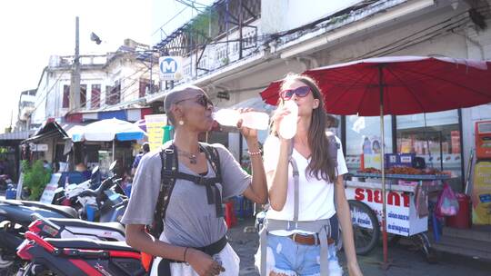 两个站在街边喝瓶装水的女人视频素材模板下载