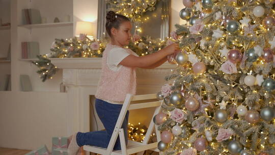 小女孩用球和装饰品装饰圣诞树