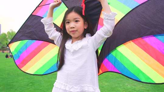 公园里拿着风筝奔跑的小女孩