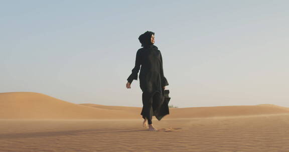 穿着黑色衣服的女人行走在沙漠里