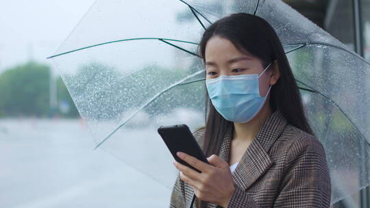 中国女性打伞步行踏春打电话等公交玩手机视频素材模板下载