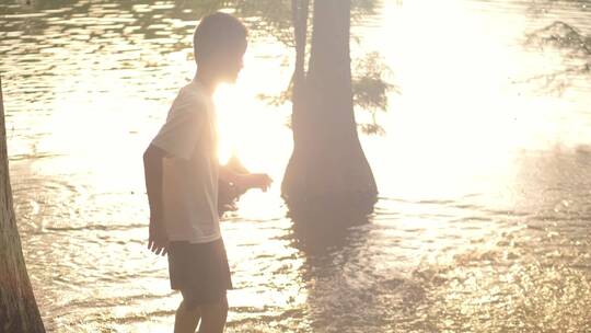 小男孩在傍晚夕阳下的水池边玩耍视频素材