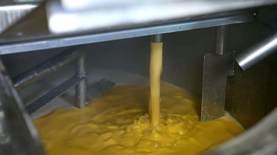 黄色液体倒入容器。黄油或奶油生产线。食品